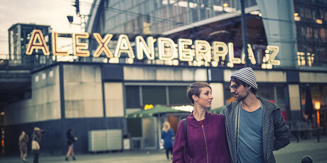 Jeune couple devant la station de S-Bahn Alexanderplatz au crépuscule