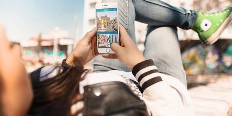 Junge Frau nutzt Streetart Highlight der ABOUT BERLIN App.
