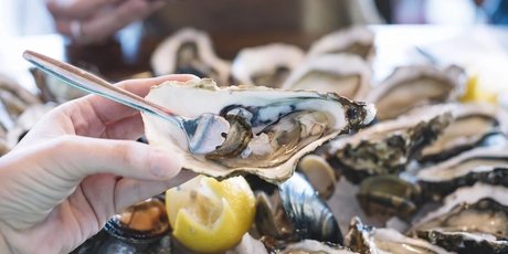 Man holding oyster, fork sticking in it