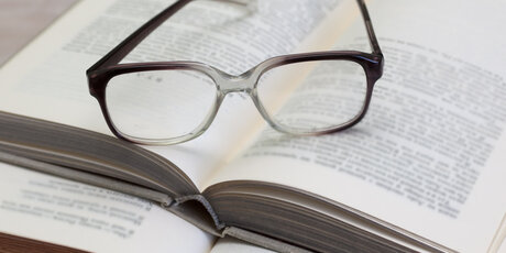 Brille und geöffnetes Buch auf einem Tisch