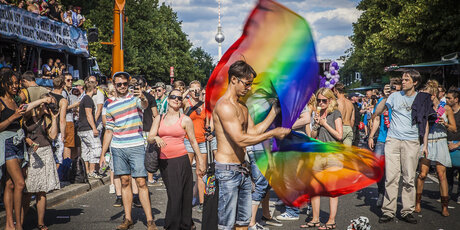 La gente con la bandera del arco iris en el Pride Parade en Berlín