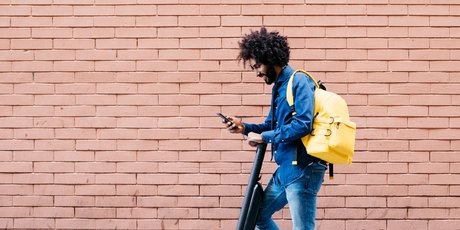 Ein Mann auf auf einem E-Roller mit Smartphone