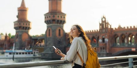 Junge Frau mit Smartphone vor der Oberbaumbrücke