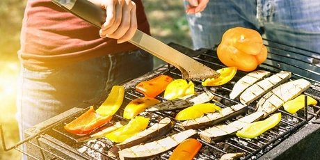 Young woman cooking vegetables for vegetarian barbecue dinner outdoor - Couple grilling peppers and aubergines for bbq - Vegan and healthy lifestyle concept - Soft focus on bottom barbecue tongs