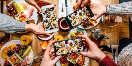 Friends taking pictures of food on the table with smartphones during brunch in restaurant