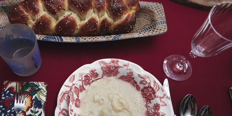 Overhead shot of a table with a loaf of challah and a plate on it.