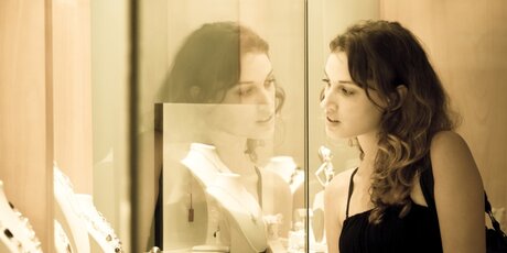 Young woman looks into glass case where jewelry is