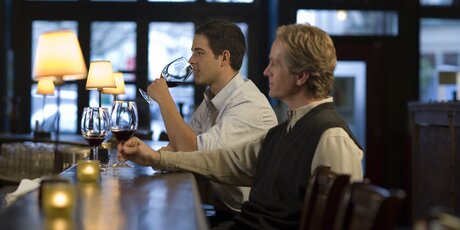 Due uomini seduti in un bar di Berlino che bevono vino