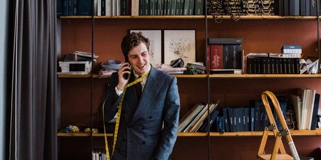 Maximilian Mogg on the phone, with a tape measure around his neck, in his shop in Berlin