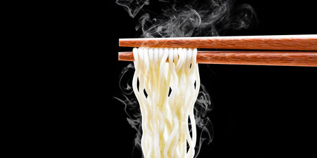 Noodles with chopsticks against a black background 