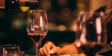 Nahaufnahme eines Sommeliers beim Servieren von Rotwein in einem gehobenen Restaurant