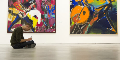 Un visitatore della Berlinische Galerie si siede sul pavimento e disegna