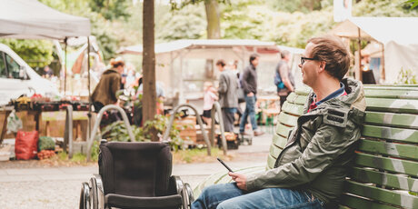 Wheelchair user on a bench in Berlin's neighbourhood