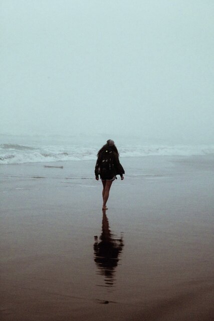 Frau spaziert an nebligem Strand