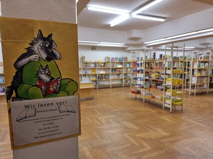 Blick in die Kinderbibliothek mit Werbeschild fürs Vorlesen