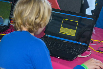 Ein Kind sitzt vor einem Notebook und spielt ein Computerspiel