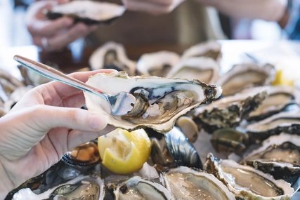 Man holding oyster, fork sticking in it