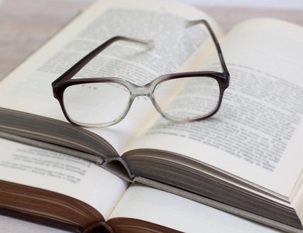 Brille und geöffnetes Buch auf einem Tisch