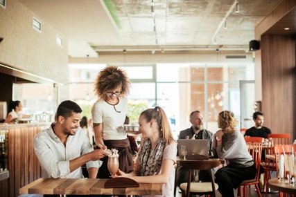Im Café Eine Kellnerin bedient ein Paar im Café in Berlin