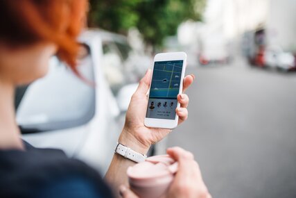 Compartir coche: una mujer en Berlín usa una aplicación en su smartphone