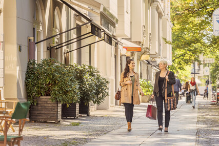 Zwei Frauen laufen auf dem Gehweg nach dem Einkaufen oder Bummeln 