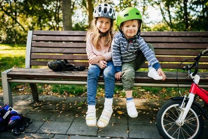 Kinder auf Parkbank mit Fahrradhelmen