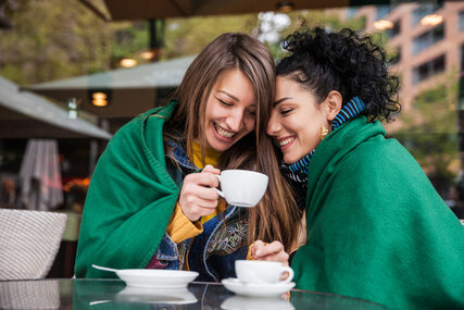 Gemeinsam unter einer Decke: Freundinnen trinen Kaffee in Berlin