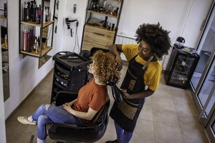 Visit to the hairdresser Hairdresser blow-drying the hair of a customer with curls