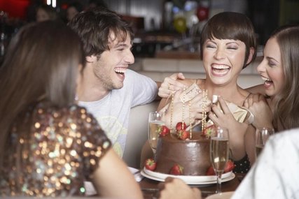Five people having fun and laughing at a birthday party in a restaurant