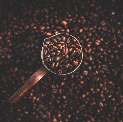Copper coffee pot with coffee beans, top view