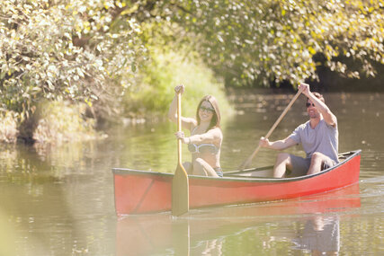 Couple rowing canoe on river