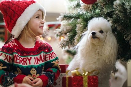 kleine Kind mit Hund vorm Weihnachtsbaum