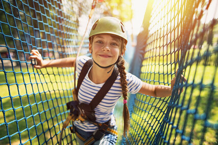 Teenage girl having fun in ropes course adventure park