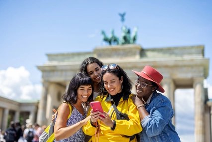 Multiracial group of women friends on vacation looking at their pictures on a smart phone