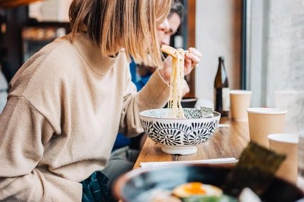Eine junge Frau isst Ramen Eine junge Frau isst Ramensuppe an einer Theke in Berlin