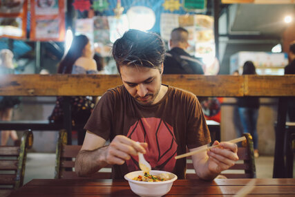 A young man eats Ramen in a restaurant