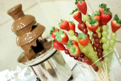 Chocolate fountain with fruit skewers Milk chocolate fountain with strawberries and grapes