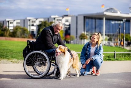 Sightseeing in Berlin's government district: wheelchair user pets a dog. Sightseeing in Berlin's government district: wheelchair user pets a dog.
