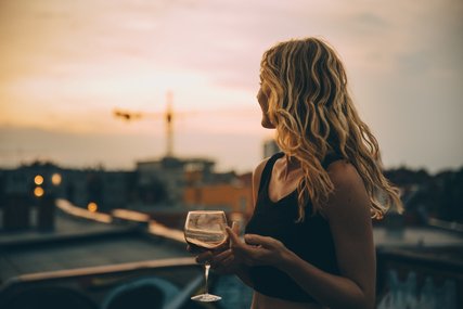 Junge Frau mit Weinglas auf Dach