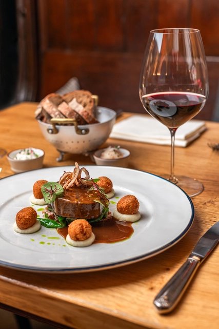 Rinderhirschfilet mit gebratenem Kalbsbries und Bratensoße, serviert mit Rotwein im Gourmet-Restaurant