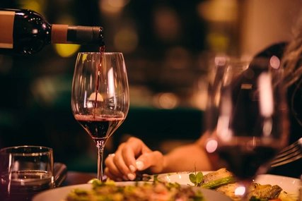 Nahaufnahme eines Sommeliers beim Servieren von Rotwein in einem gehobenen Restaurant