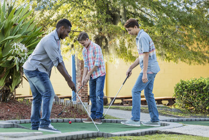 Young people play mini golf 