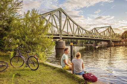 Zwei Radfahrer machen Pause an der Glienicker Brücke in Berlin