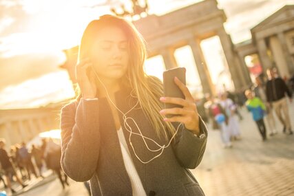 Young woman listening to audio tour at Brandenburg Gate.