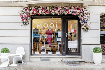 Fassade Mooi Fashion mit Blumendekoration und Sitzgelegenheit