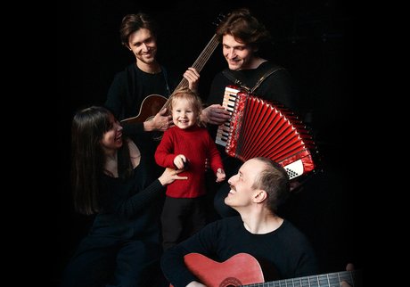 Eine Frau und drei Männer haben sich um ein Mädchen mit rotem Pulli versammelt.