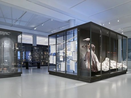 Ausstellungsansicht des Moduls "Schaumagazin Afrika. Objektaneignung und Afrika-Illusionen" des Ethnologischen Museums im Humboldt Forum, rechts im Bild ein textiles Kunstwerk der namibischen Modekünstlerin Cynthia Schimming