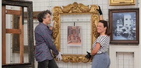 Blick in das Rahmenrestaurierungsatelier. Bertram Lorenz (li.) und Nadin Radecke (re.) stehen vor dem Sansovino-Rahmen.