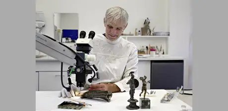 Restaurator Uwe Peltz bei der Reinigung einer römischen Bronzestatuette der Minerva von Korrosion.