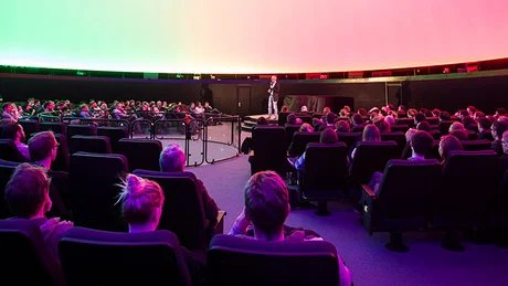 Mann, der seinen Science Slam in der Planetariumskuppel des Zeiss-Großplanetariums hält.